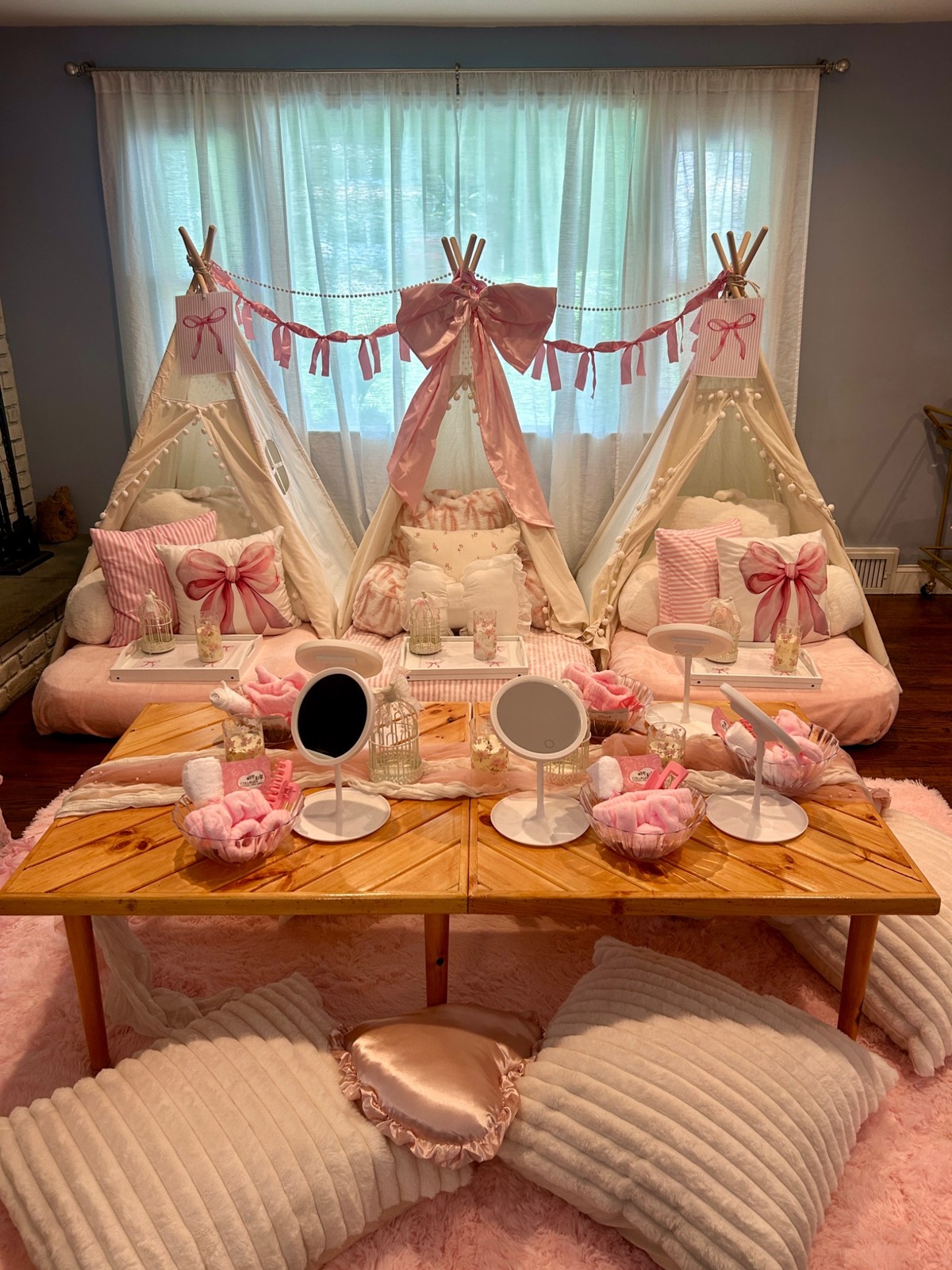 Pink bow tent sleepover and low picnic table with mirrors, cushions and spa details