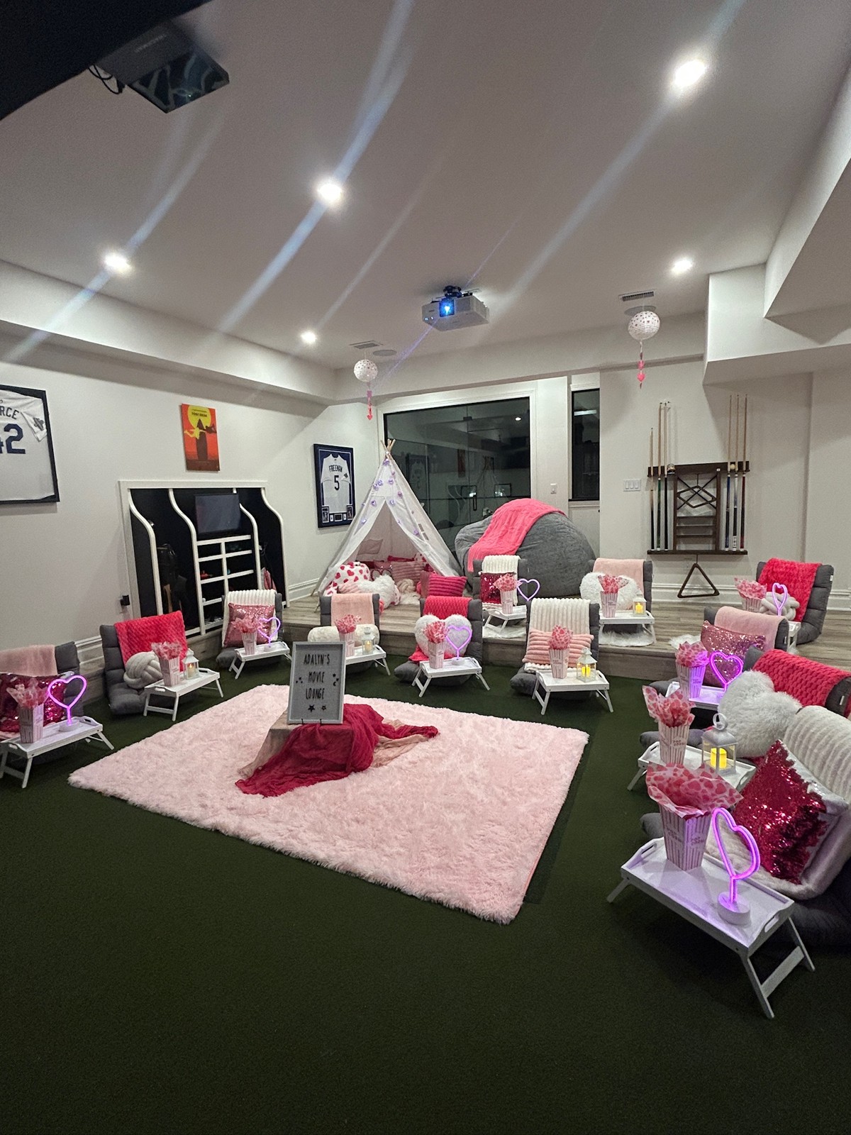 Indoor lounge chairs arranged around a pink rug with bright pink party decor