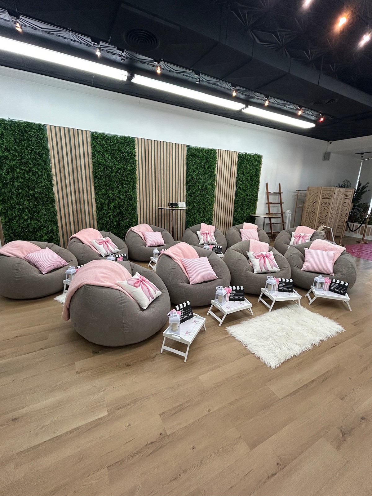 Gray lounge chairs with pink cushions and bows arranged for an indoor celebration