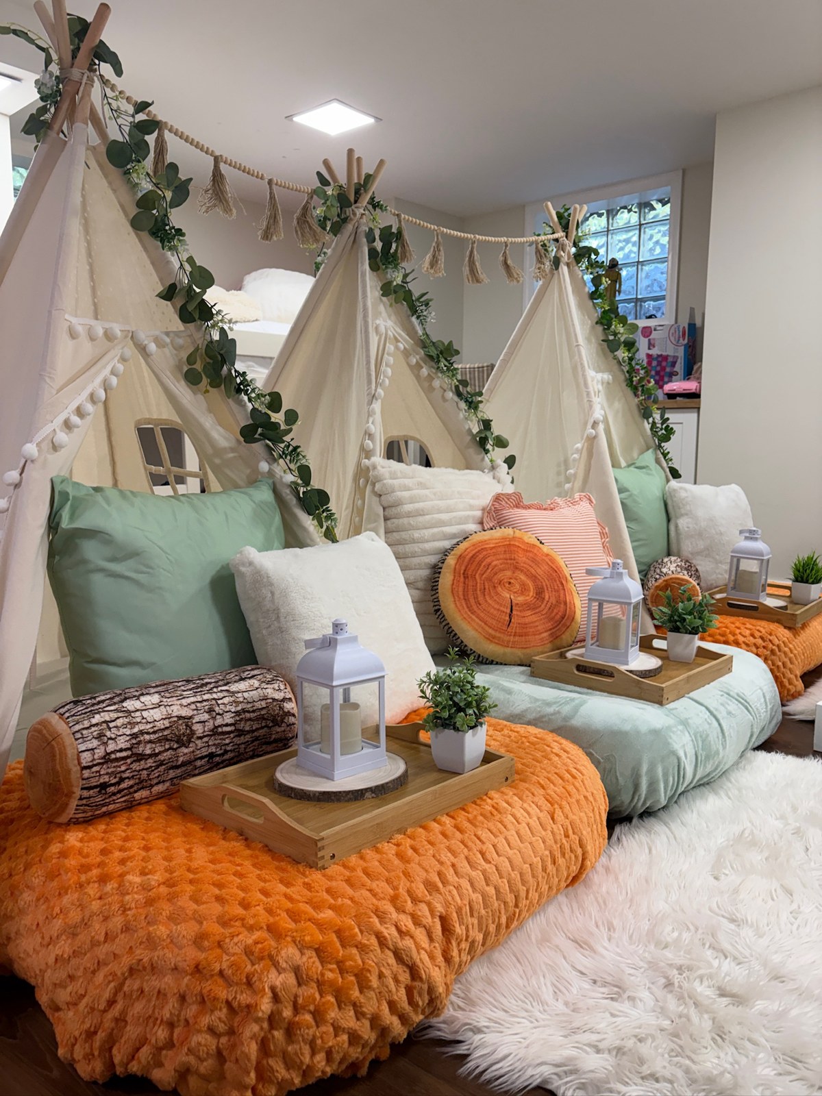 Woodland Dreams tent sleepover with leafy garlands, mint bedding and orange blankets